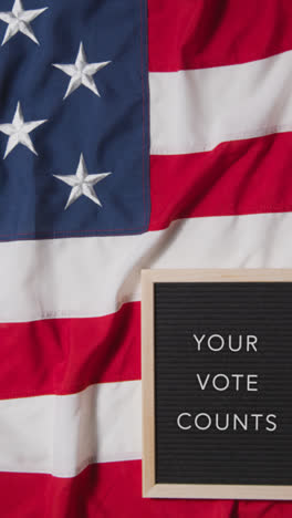 Vertical-Video-Of-Animated-Sign-Spelling-Out-Your-Vote-Counts-Lying-On-US-Stars-And-Stripes-Flag-For-American-Election-2024